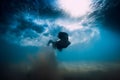 Woman dive without surfboard under wave. Underwater duck dive under wave and sandy bottom