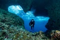 woman diver underwater at the entrance of a cave with sunrays Royalty Free Stock Photo