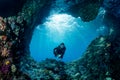 woman diver underwater at the entrance of a cave with sunrays Royalty Free Stock Photo