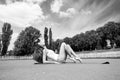 Woman do pilates on yoga mat. Sensual woman relax on stadium. Fashion athlete practice yoga outdoor. Wellness and