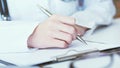 Female medicine doctor hand holding silver pen writing something on clipboard closeup. Royalty Free Stock Photo