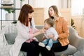 Woman doctor giving spoon dose of medicine liquid drinking syrup to child baby girl her patient. Doctor visit at home Royalty Free Stock Photo