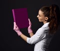 Woman doctor gynecologist reproductologist in pink latex gloves and uniform standing and holding purple album