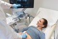 Woman and doctor looking at ultrasonic screen during examination