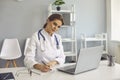 Woman doctor making notes during online lesson or video call consultation in medical clinic Royalty Free Stock Photo