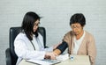 Woman doctor measuring blood pressure for elderly female patient on the doctor\'s office desk. Elderly female patient Royalty Free Stock Photo