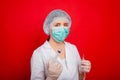 Woman doctor in medical clothes holds a syringe and an ampoule in her hands. Studio photo on a red background. Royalty Free Stock Photo