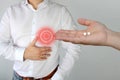 Woman, doctor, nurse, holds out white palm pills to a man in a shirt with a red circle, a symbol of throbbing pain that holds on