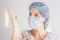 Woman doctor nurse wearing medical mask and hat, putting on disposable gloves. Protection from coronavirus infection, health care Royalty Free Stock Photo