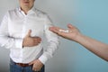 Woman doctor, nurse, wife holds out white pills in the palm of a man in a shirt who is holding his chest in the heart, medical