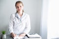 Woman doctor in an office with daylight. Healthcare specialist at the table. Authentic people