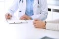 Woman doctor and patient sitting and talking at medical examination at hospital office, close-up. Physician filling up Royalty Free Stock Photo