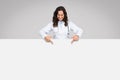 Woman doctor pointing down at an empty banner Royalty Free Stock Photo