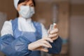 Woman doctor in a protective mask in blue medical clothes holding a syringe in her hand. The nurse is going to make an injection, Royalty Free Stock Photo