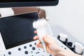 Woman doctor's hand aholding a medical gel to ultrasonic sensor of ultrasound machine in the clinic