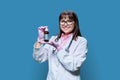 Woman doctor showing glass liquid medicine bottle, blue studio background Royalty Free Stock Photo