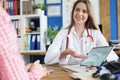 Woman doctor showing information to patient on digital tablet in clinic Royalty Free Stock Photo