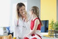 Woman doctor showing little girl blister with medication in clinic