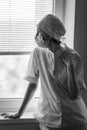 A woman doctor in a state of stress looking out the window. Black and white photo. Royalty Free Stock Photo