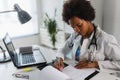 Woman doctor with stethoscope looking at medical papers at her office working hard Royalty Free Stock Photo