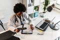 Woman doctor with stethoscope looking at medical papers at her office working hard Royalty Free Stock Photo