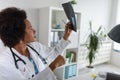 Woman doctor with stethoscope looking at medical papers at her office working hard Royalty Free Stock Photo