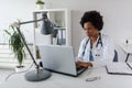 Woman doctor with stethoscope looking at medical papers at her office working hard Royalty Free Stock Photo