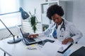Woman doctor with stethoscope looking at medical papers at her office working hard Royalty Free Stock Photo