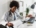 Woman doctor with stethoscope looking at medical papers at her office working hard Royalty Free Stock Photo