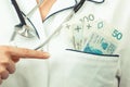 Woman doctor with stethoscope showing polish currency money in apron pocket Royalty Free Stock Photo