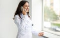 Woman doctor talking on phone, consulting patient, looking through window Royalty Free Stock Photo