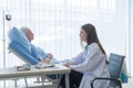 Woman doctor talking about sad news to depressed sick old female senior elderly patient lying in bed in hospital ward room in Royalty Free Stock Photo