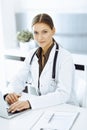 Woman-doctor typing on laptop computer while sitting at the desk in hospital office. Data in medicine and healthcare Royalty Free Stock Photo