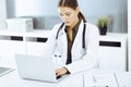 Woman-doctor typing on laptop computer while sitting at the desk in hospital office. Data in medicine and healthcare Royalty Free Stock Photo