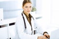 Woman-doctor typing on laptop computer while sitting at the desk in hospital office. Physician at work Royalty Free Stock Photo