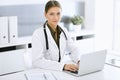 Woman-doctor typing on laptop computer while sitting at the desk in hospital office. Physician at work. Data in medicine Royalty Free Stock Photo