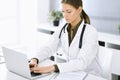 Woman-doctor typing on laptop computer while sitting at the desk in hospital office. Physician at work. Data in medicine Royalty Free Stock Photo