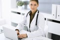 Woman-doctor typing on laptop computer while sitting at the desk in hospital office. Physician at work. Data in medicine Royalty Free Stock Photo