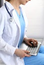 Woman doctor typing on laptop computer while working in hospital office, close-up. Data in medicine and health care Royalty Free Stock Photo