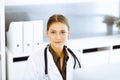 Woman-doctor typing on pc computer while sitting at the desk in hospital office. Physician at work Royalty Free Stock Photo