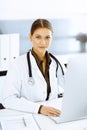 Woman-doctor typing on pc computer while sitting at the desk in hospital office. Physician at work Royalty Free Stock Photo