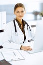 Woman-doctor typing on pc computer while sitting at the desk in hospital office. Physician at work Royalty Free Stock Photo