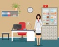 Woman doctor in uniform standing near the desk in doctors office. Medical consulting room interior