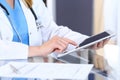 Woman doctor using tablet computer while sitting at the desk in hospital office, closeup. Healthcare, insurance an Royalty Free Stock Photo