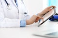 Woman doctor using tablet computer while standing straight in hospital closeup. Healthcare, insurance and medicine Royalty Free Stock Photo