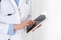 Woman doctor using tablet computer while standing straight in hospital closeup. Healthcare, insurance and medicine Royalty Free Stock Photo