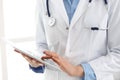 Woman doctor using tablet computer while standing straight in hospital closeup. Healthcare, insurance and medicine Royalty Free Stock Photo