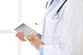 Woman doctor using tablet computer while standing straight in hospital closeup. Healthcare, insurance and medicine Royalty Free Stock Photo