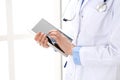 Woman doctor using tablet computer while standing straight in hospital closeup. Healthcare, insurance and medicine Royalty Free Stock Photo