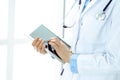 Woman doctor using tablet computer while standing straight in hospital closeup. Healthcare, insurance and medicine Royalty Free Stock Photo